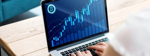 Persona utilizando una laptop con gráfico financiero de velas y líneas ascendentes en pantalla, con símbolo de Bitcoin, representando análisis de criptomonedas. Persona utilizando una laptop con gráfico financiero de velas y líneas ascendentes en pantalla, con símbolo de Bitcoin, representando análisis de criptomonedas.