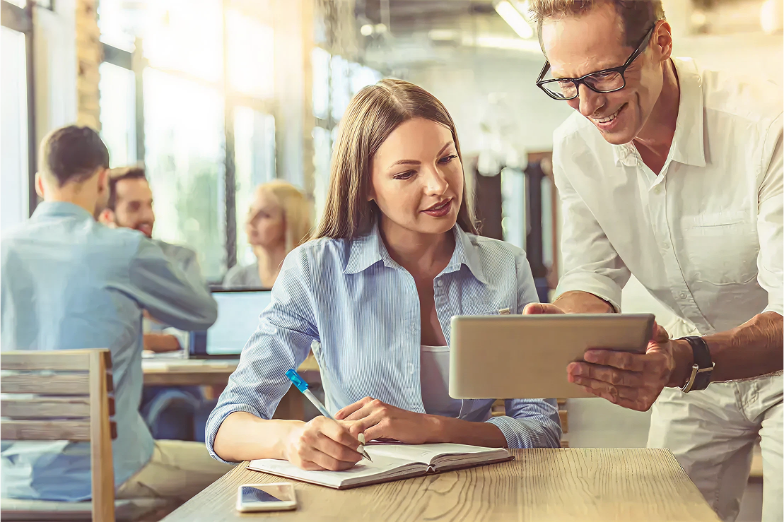 Fotografía de un hombre y una mujer revisando una tableta digital en un ambiente laboral colaborativo.